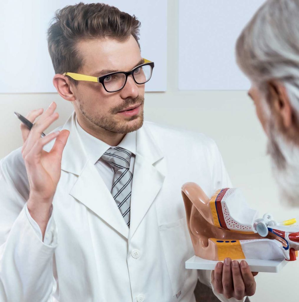 Man speaking to hearing expert and learning about real ear measurement. 